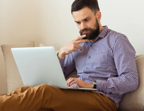 Pemuda berjanggut bekerja pada laptop di rumah — Stok Foto