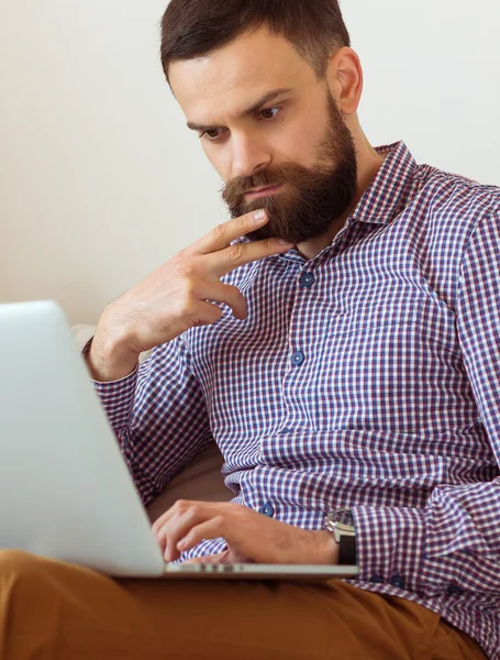 Jovem barbudo trabalhando no laptop — Fotografia de Stock