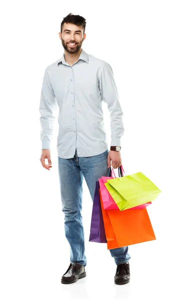 Bonito homem segurando sacos de compras no fundo branco — Fotografia de Stock