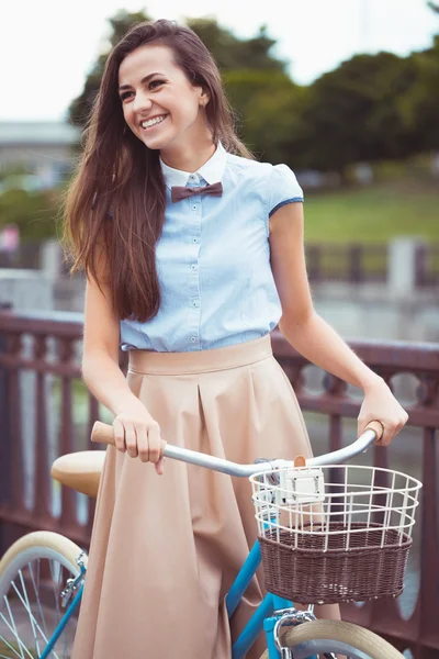 Joven mujer hermosa, elegantemente vestida con bicicleta a la par — Foto de Stock