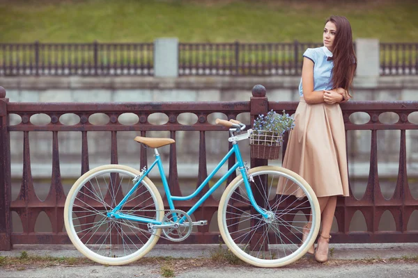 Joven mujer hermosa, elegantemente vestida con bicicleta a la par — Foto de Stock