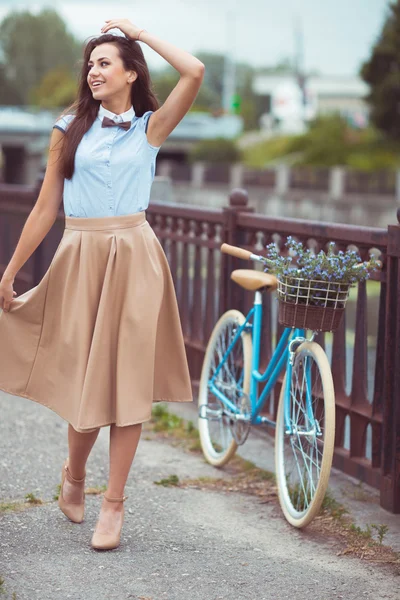 Joven mujer hermosa, elegantemente vestida con bicicleta a la par — Foto de Stock