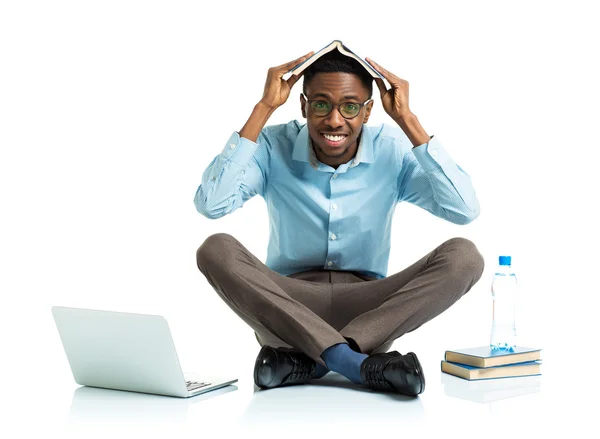 Happy african american college student sitting on white with lap — Stock Photo, Image
