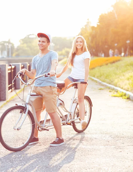 Happy couple riding a bicycle in the park outdoors — Stock Photo, Image