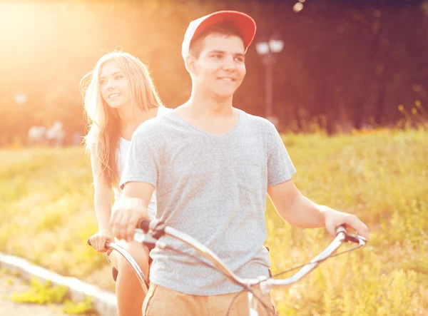 Happy couple riding a bicycle in the park outdoors — Stock Photo, Image