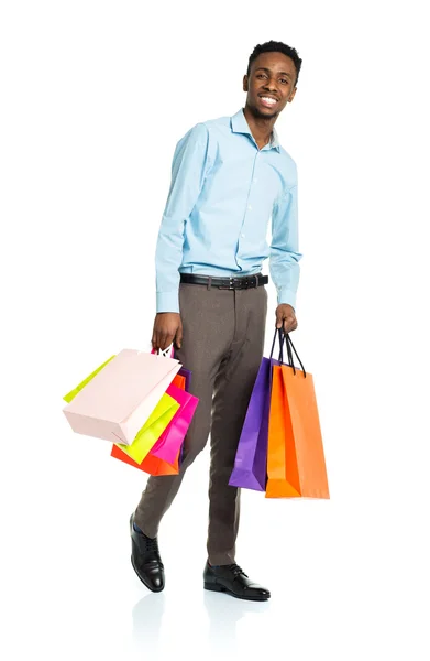 Feliz afroamericano hombre sosteniendo bolsas de compras en blanco backgr —  Fotos de Stock