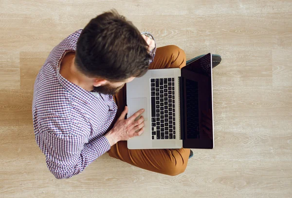 Pemandangan atas pria yang duduk di lantai dan bekerja dengan laptop — Stok Foto