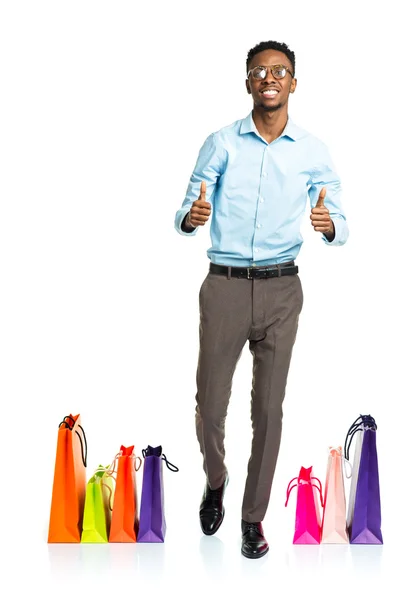 Happy african american man with thumbs up and shopping bags on w — Stock Photo, Image