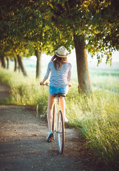 Encantadora joven con un sombrero montando una bicicleta al aire libre. Activo pe — Foto de Stock
