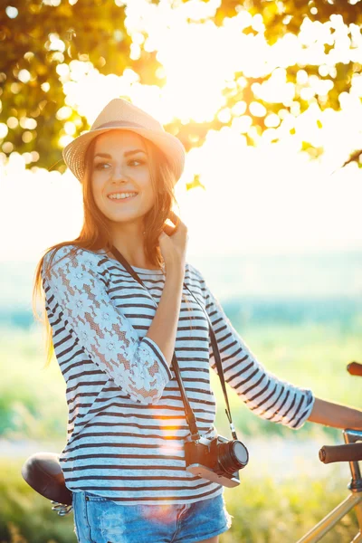 Lovely young woman in a hat riding a bicycle outdoors. Active pe — Stock Photo, Image