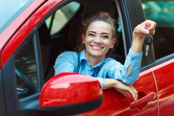 Jovem mulher alegre sentada em um carro com as chaves na mão — Fotografia de Stock