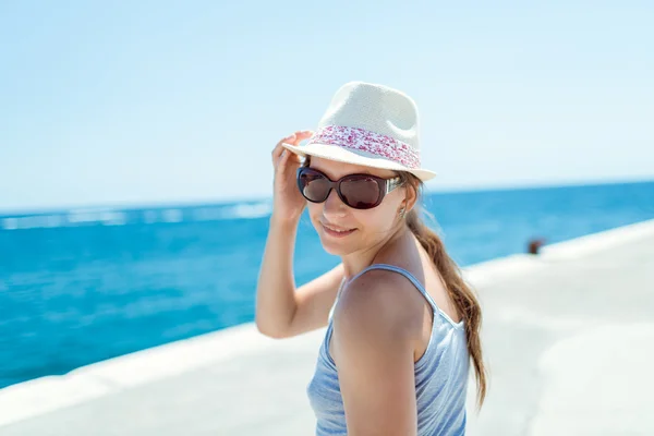 Fille sur le front de mer en lunettes de soleil et chapeau — Photo