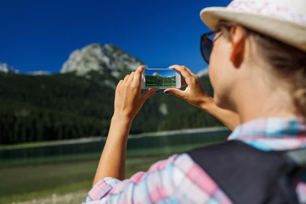 A menina no chapéu faz uma foto de smartphone do Lago Negro , — Fotografia de Stock