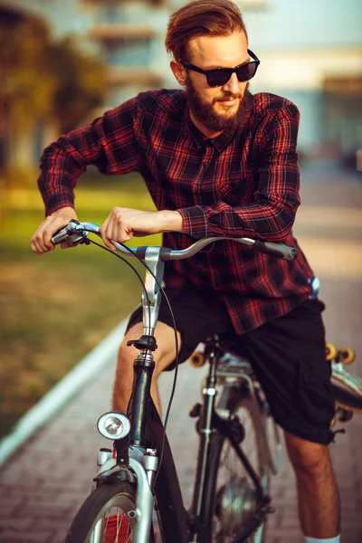 Stylish man in sunglasses riding a bike on city street — Stock Photo, Image