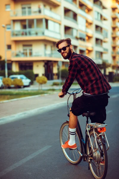 Uomo elegante in occhiali da sole in bicicletta sulla strada della città — Foto Stock