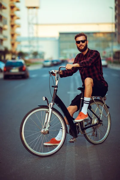 Uomo elegante in occhiali da sole in bicicletta sulla strada della città — Foto Stock