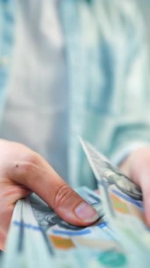 Amerikan Doları 'nı sayan bir kadın, yakın plan. Yatırım, başarı, finansal beklentiler veya kariyer gelişimi kavramı. Dikey video