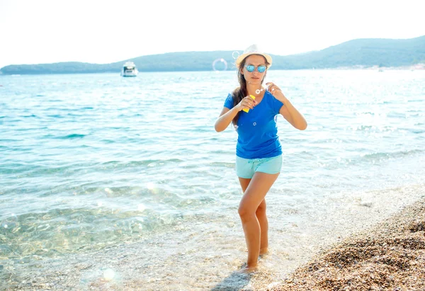 Mutlu genç kız sahil üzerinde sabun köpüğü üfleme — Stok fotoğraf