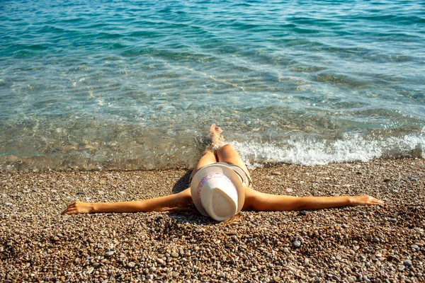 Mujer joven en un sombrero y bikini acostado en la playa en verano caliente —  Fotos de Stock