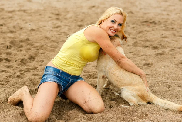 Mulher com cão brincando na praia — Fotografia de Stock