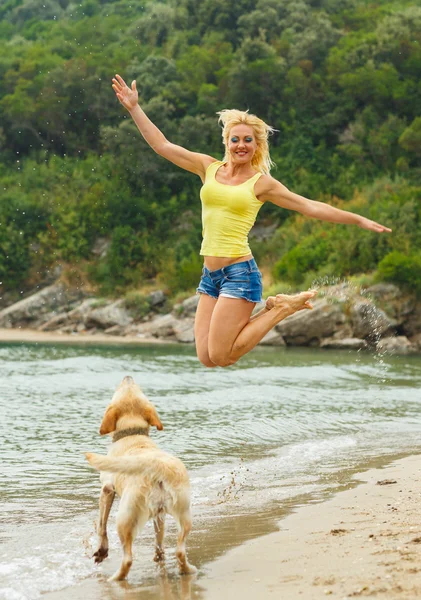 Woman with dog playing on the beach — Stock Photo, Image
