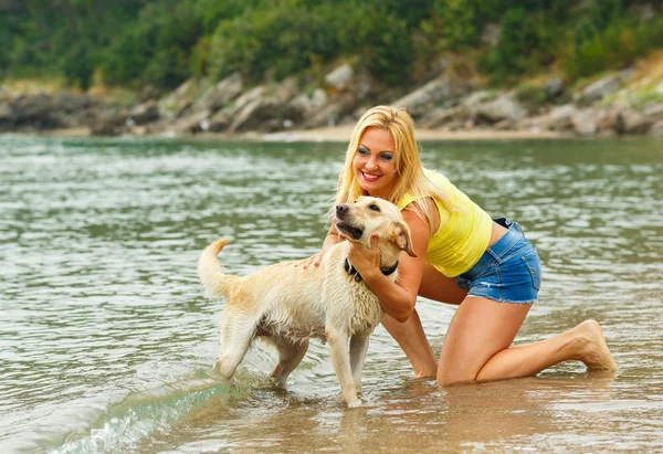 Kvinna med hund spelar på stranden — Stockfoto