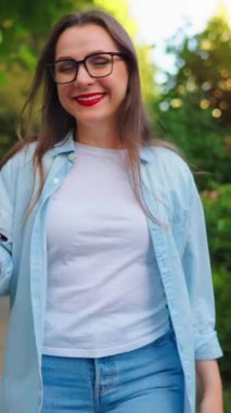 Elinde akıllı telefonuyla mutlu bir kadın çiçek açan bahçede ya da iş gününden sonra yeşil sokakta yürüyor. Yavaş çekim