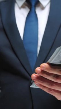 Resmi olarak giyinmiş bir adam Amerikan dolarlarını sayıyor, yakın plan. Yatırım, başarı, finansal beklentiler veya kariyer ilerlemesi kavramı.