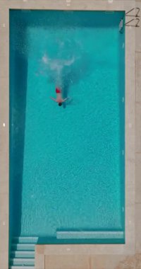 Top down view as a man dives into the pool and swims. Slow motion