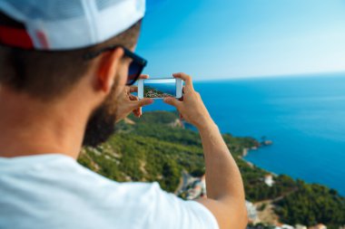 Adam yanında bir smartphone Yalı arka plan üzerinde fotoğraf yapar,