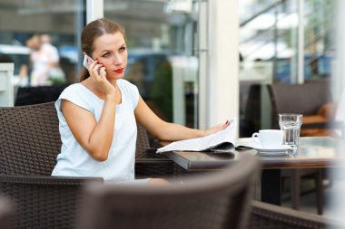 Bir gazete okuma ve bir cep telefonu dikkat konuşuyor genç kadın