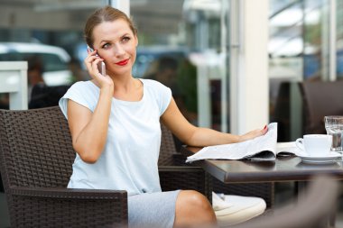 Bir gazete okuma ve bir cep telefonu dikkat konuşuyor genç kadın