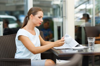 Bir gazete okuyor ve sabah kahve içme çekici kadın