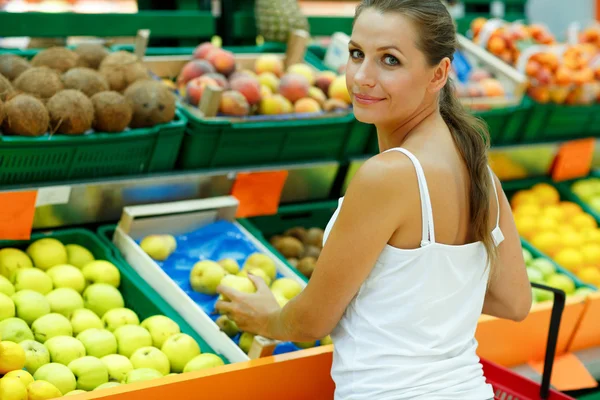 Young woman shopping in a supermarket in the department of fruit — Stok fotoğraf