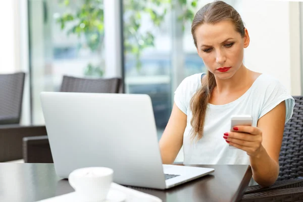 Donna attraente seduta in un caffè con un computer portatile e parlando — Foto Stock