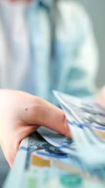 Amerikan Doları 'nı sayan bir kadın, yakın plan. Yatırım, başarı, finansal beklentiler veya kariyer gelişimi kavramı. Finansal okuryazarlık ve planlama. Dikey video
