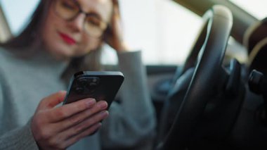 Arabada beklerken akıllı telefon kullanan mutlu bir kadının portresi..