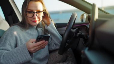 Arabada beklerken akıllı telefon kullanan mutlu güzel bir kadının portresi. Yavaş çekim