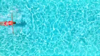 Pembe mayo giymiş bir kadının havuzda sırt üstü yüzüşü. Rahatlatıcı konsept, yaz yaşam tarzı.