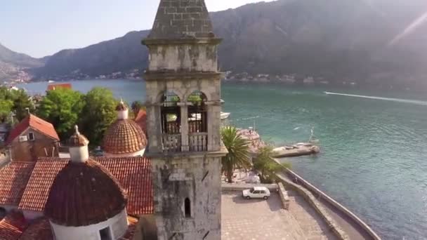 Vliegen over de oude kerk aan de oever van de baai van Kotor — Stockvideo