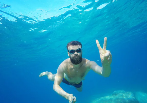 Человек, делающий подводное селфи с селфи-палкой в море — стоковое фото