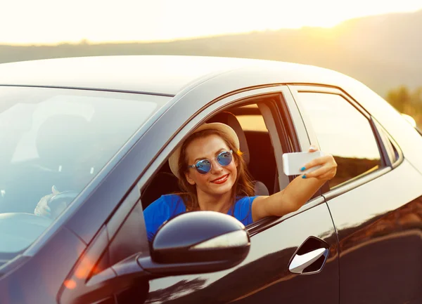 Mujer joven en sombrero y gafas de sol haciendo autorretrato sentado i — Foto de Stock