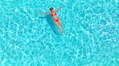 Pembe mayo giymiş bir kadının havuzda sırt üstü yatışı. Rahatlatıcı konsept, yaz yaşam tarzı. Yavaş çekim.