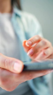 Kurye uygulaması kullanarak akıllı telefondan sosyal medya kaynaklarını tarayan bir kadın. Elinde cep telefonu olan bir kadın. Dikey