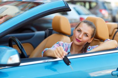 Bir Cabrio araba anahtarları elinde oturan genç kadın