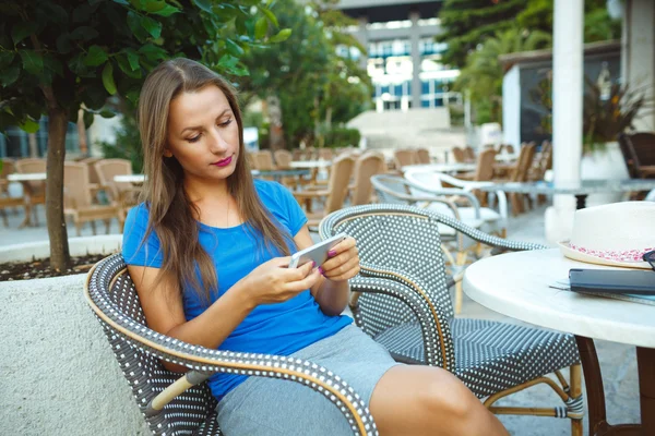 Junge Frau entspannt sich im Outdoor-Café und nutzt Smartphone — Stockfoto