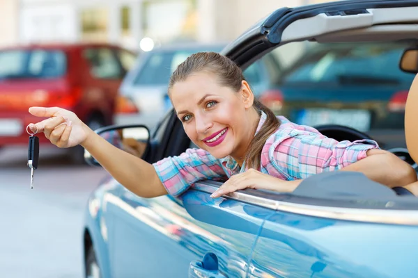 Mujer joven sentada en un coche descapotable con las llaves en la mano —  Fotos de Stock