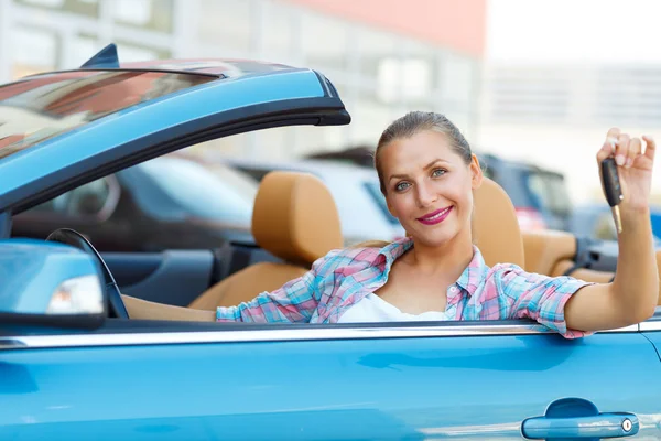 Mujer joven sentada en un coche descapotable con las llaves en la mano — Foto de Stock