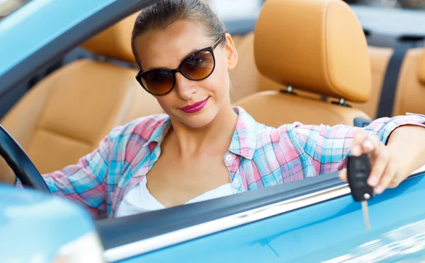 Mulher de óculos de sol sentado em um carro conversível com as chaves i — Fotografia de Stock