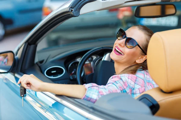 Mujer en gafas de sol sentada en un coche convertible con las llaves i — Foto de Stock